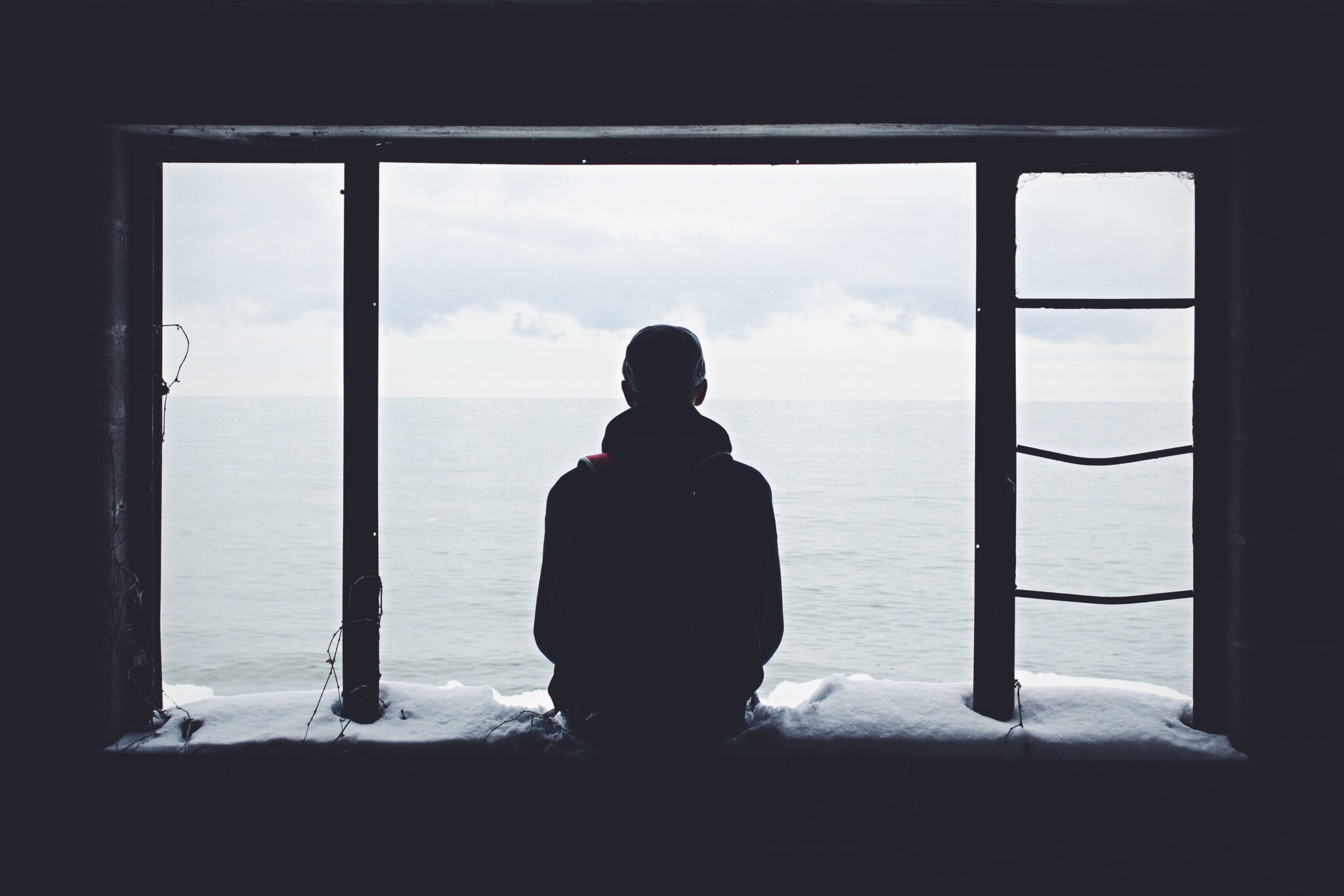 man sitting at window looking at ocean